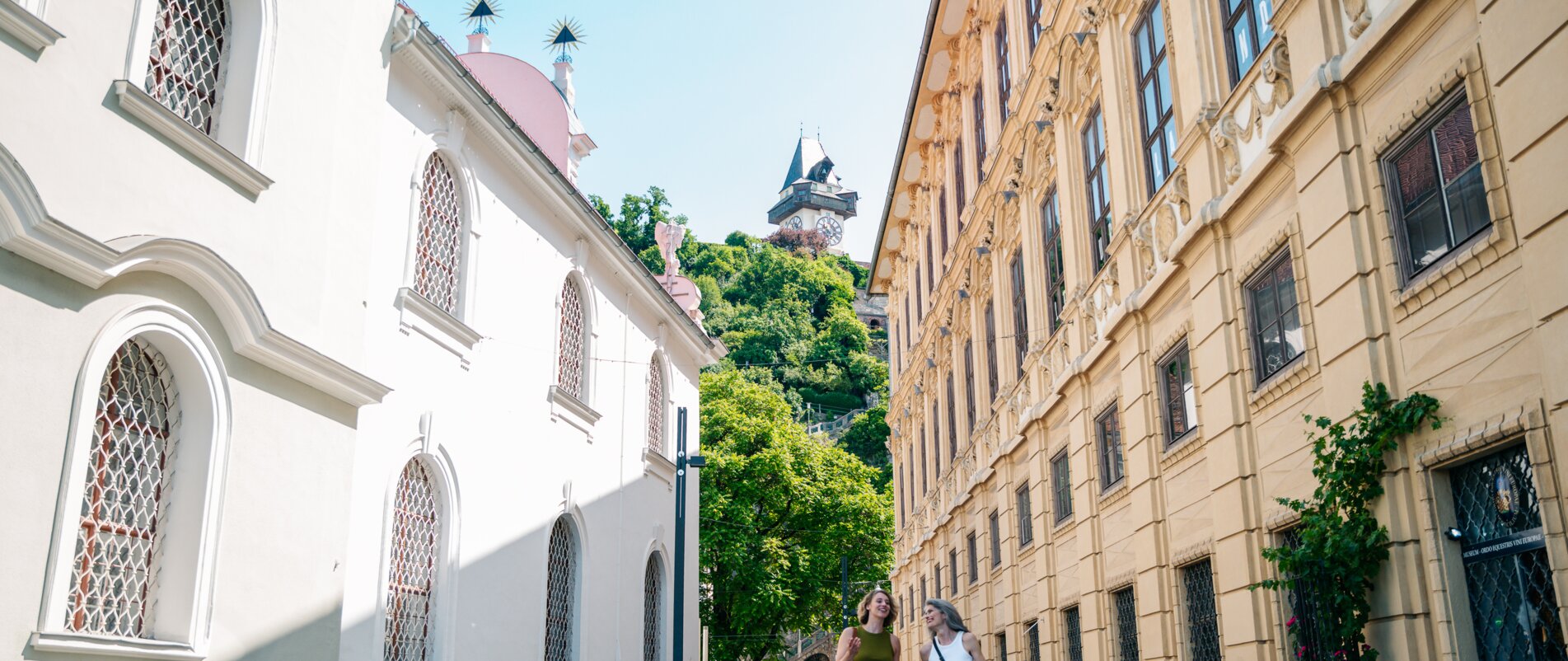 Schlossbergplatz in Graz with Clock Tower | © Graz Tourismus - Mias Photoart Two women walking at Schlossbergplatz in Graz, Clock Tower in the background. | © Graz Tourismus - Mias Photoart