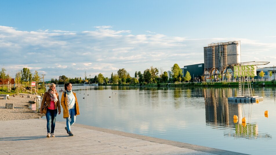 Spaziergang: Ab in den Süden von Graz I Wandern & Spazieren in Graz | © Graz Tourismus Zwei Frauen gehen am Flussufer entlang - bei Sonnenuntergang in Graz. | © Graz Tourismus