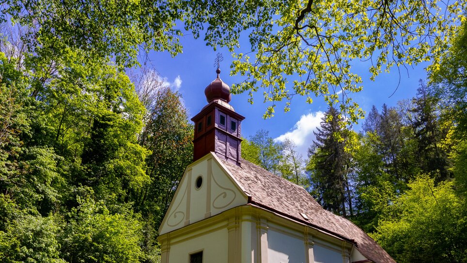 Wallfahrtskirche Ulrichtsbrunn umgeben von grünem Wald und strahlendem Himmel. | © Graz Tourismus