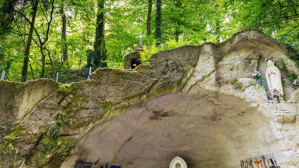 Ein Altar in einer Höhle in Ulrichsbrunn, umgeben von Bäumen und Andenken.
