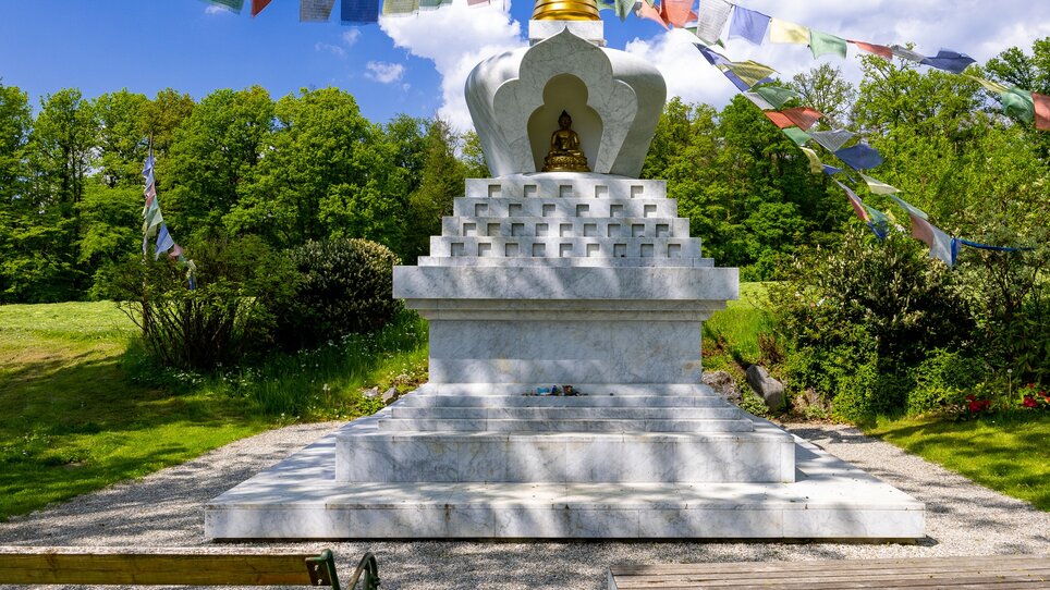 Stupa in der Natur mit Gebetsfahnen, friedliche Umgebung. | © Graz Tourismus