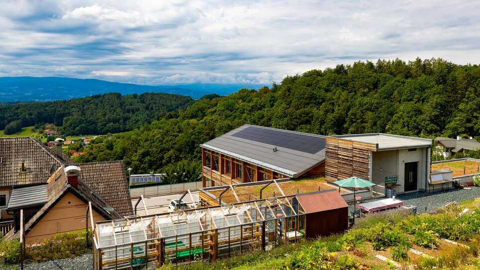 View of nature and buildings in Graz, surrounded by green forest under a clear sky. | © Graz Tourismus
