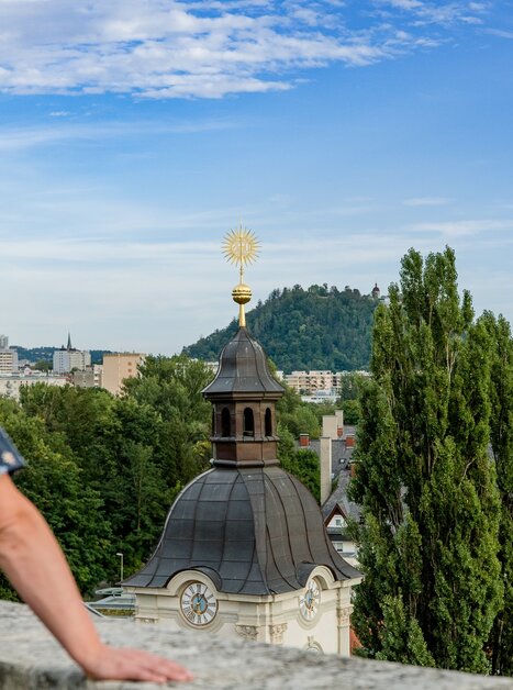 Man looking over Graz with the Schlossberg in the background | © Graz Tourismus