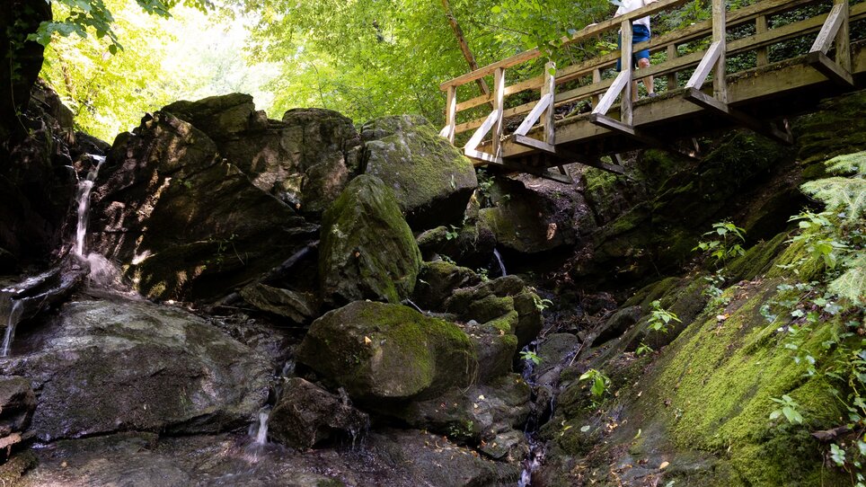 A hike in Rettenbach gorge with a bridge over the waterfall and lush greenery. | © Graz Tourismus