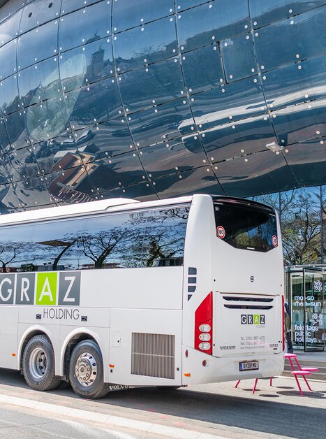 Ein Bus von Graz Holding steht vor dem Kunsthaus Graz in der Stadt Graz. | © achtzigzehn - Hinterleitner