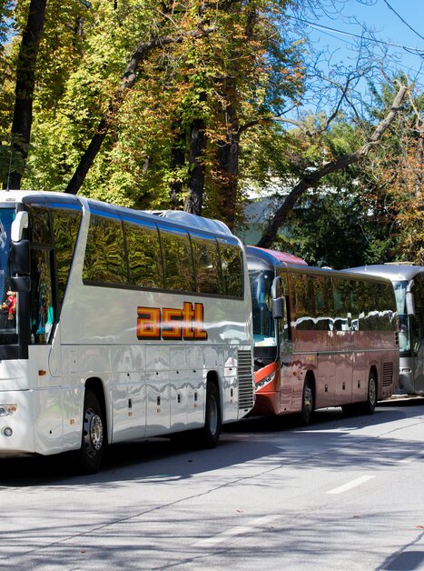 Mehrere Reisebusse parken in einer Straße in Graz, umgeben von Bäumen. | © Graz Tourismus - Harry Schiffer