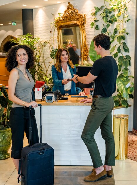 Gast wird an der Rezeption empfangen, mit Koffer. | © Graz Tourismus - Mias Photoart
