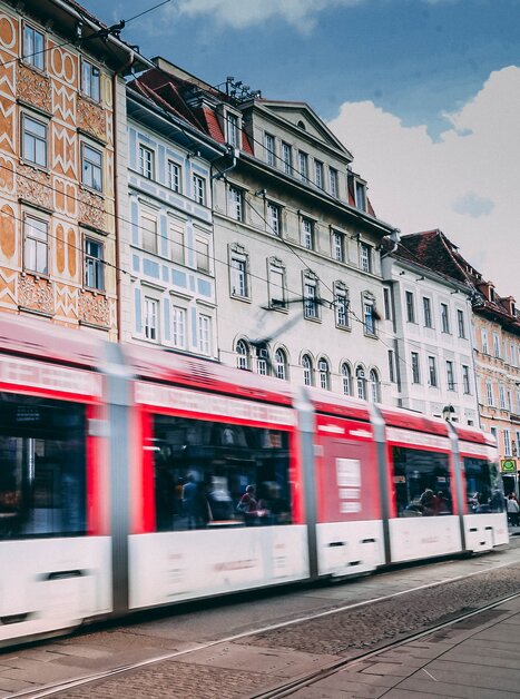Eine Straßenbahn in Graz fährt an einer bunten Fassade am Grazer Hauptplatz vorbei. Der Swarovski Shop ist im Hintergrund zu sehen. | © Janet Newenham-Journalist on the Run