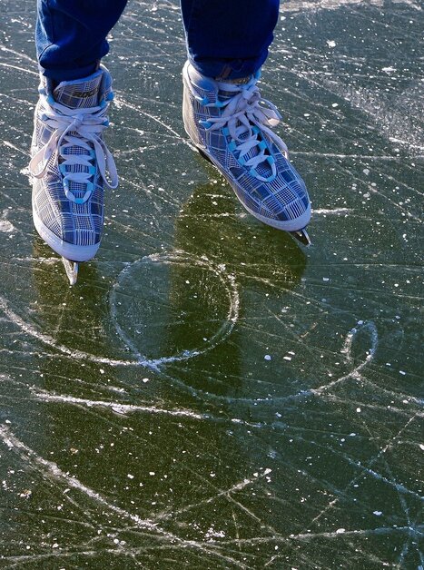 Person in ice skates on frozen lake with scratch marks. | © Pixabay