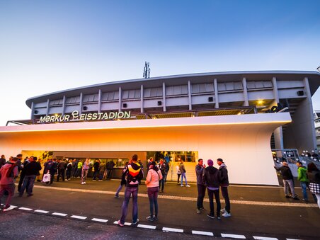Visitors stand in front of the Merkur Ice Stadium in Graz at sunset. | © MCG - Krug