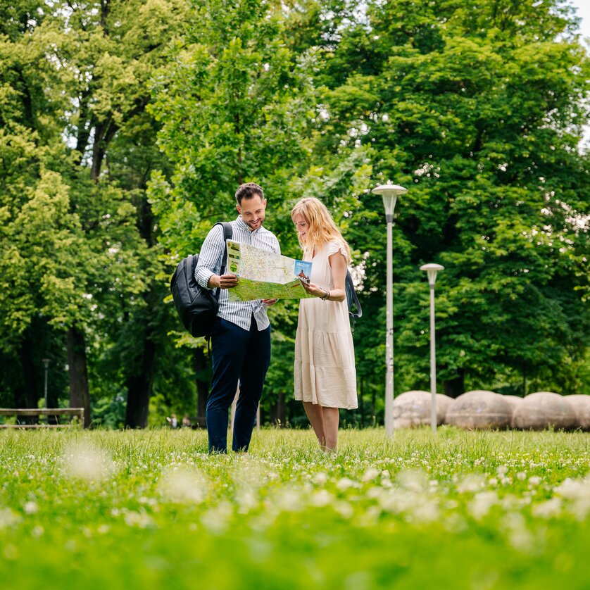 Coppia in Augarten che guarda una mappa. | © Graz Tourismus - Mias Photoart