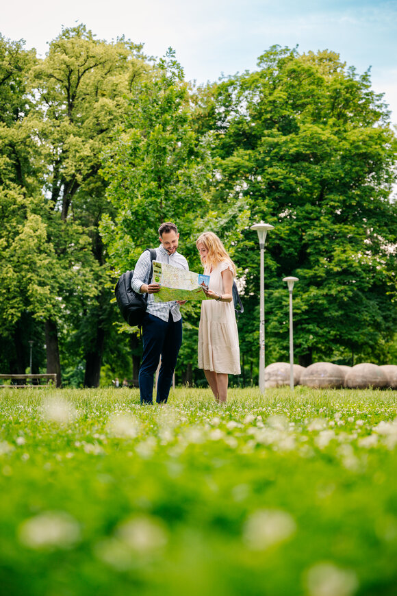 Paar steht im Augarten, schaut auf eine Landkarte. | © Graz Tourismus - Mias Photoart
