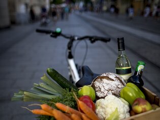 Una bicicletta con un cestino pieno di prodotti freschi nella città di Graz. | © Graz Tourismus - Tom Lamm