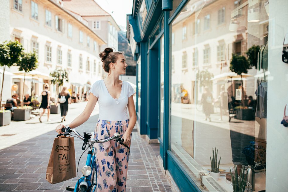A woman in Graz looks into a shop window while holding a shopping bag. | © Graz Tourismus