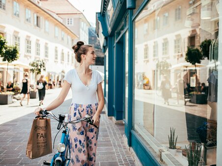 Eine Frau in Graz schaut in ein Schaufenster und hält eine Einkaufstüte. | © Graz Tourismus