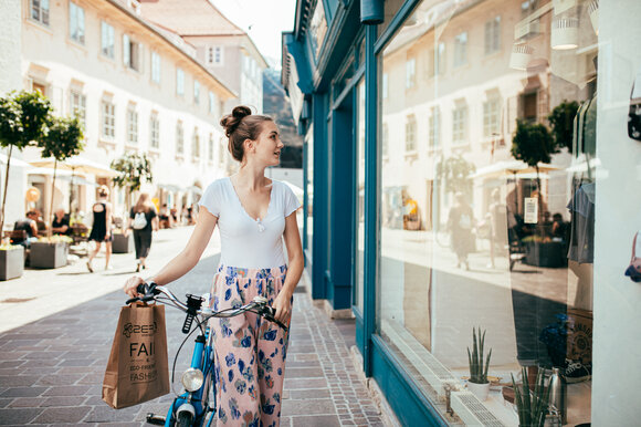 Eine Frau in Graz schaut in ein Schaufenster und hält eine Einkaufstüte. | © Graz Tourismus