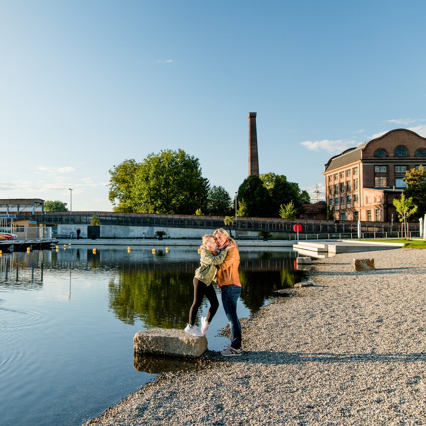 The Stadtstrand in Graz | © Graz Tourismus - Mias Photoart Mother and daughter embrace on the banks of the Mur at the Stadtstrand in Graz during sunset. | © Graz Tourismus - Mias Photoart