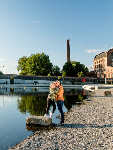 Mutter und Tochter umarmen sich am Ufer der Mur beim Stadtstrand in Graz bei Sonnenuntergang. | © Graz Tourismus - Mias Photoart