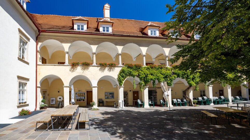 Innenhof mit Arkaden und Bäumen, strahlend blauer Himmel. | © Graz Tourismus - Harry Schiffer