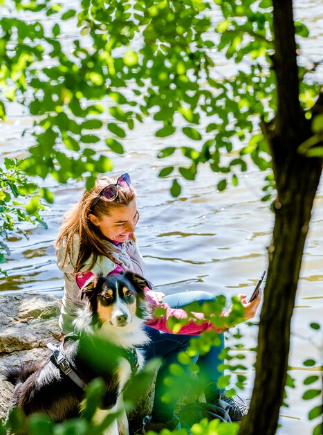 Frau mit Hund am Wasser, umgeben von Pflanzen. | © Graz Tourismus - Mias Photoart-26