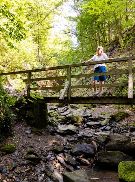 Eine Person steht auf einer Holzbrücke in einer bewaldeten Schlucht. | © Graz Tourismus - Harry Schiffer
