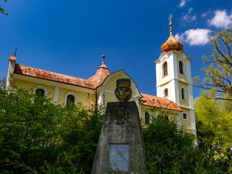 A church surrounded by trees and a monument in the foreground. | © Graz Tourismus - Harry Schiffer