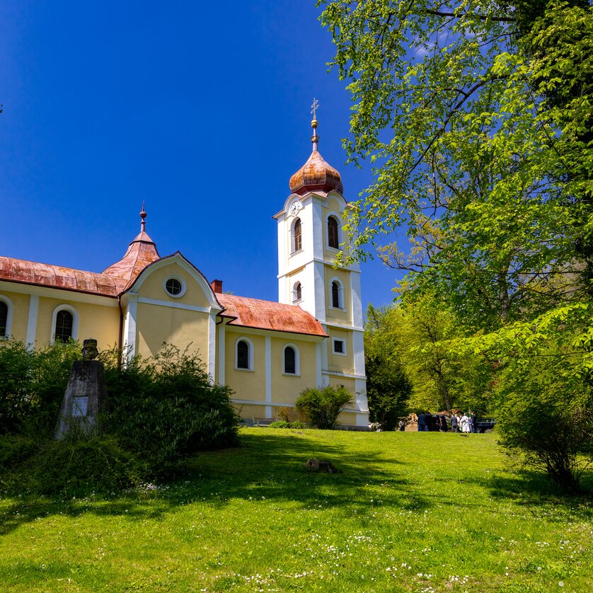Eine Kirche umgeben von Bäumen und Gras an einem sonnigen Tag. | © Graz Tourismus - Harry Schiffer