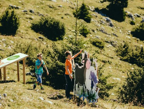 Three children playing outdoors interacting with a backdrop on Schöckl in Graz. | © Lupi Spuma