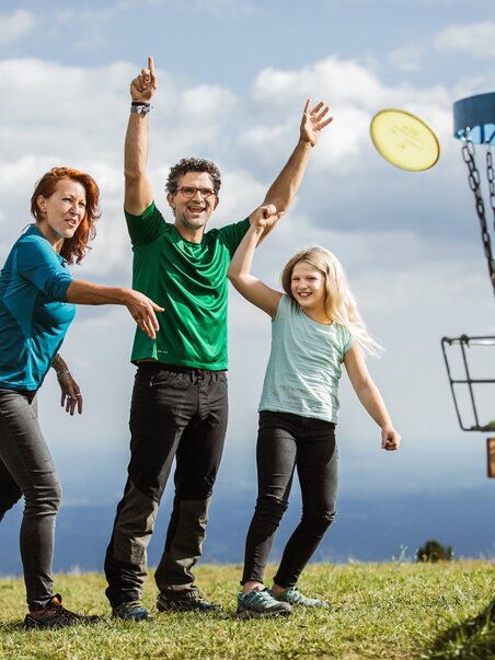 Happy family playing Frisbee disc golf on Schöckl in Graz. | © Holding Graz - Lex Karelly