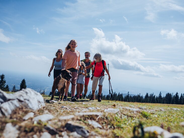Fünf Personen wandern mit einem Hund auf dem Schöckl in Graz. | © Lex Karelly