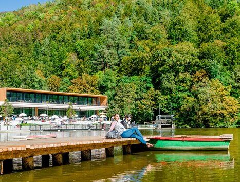 Eine Frau sitzt am Steg am Thalersee mit ihrem Hund. | © Graz Tourismus - Mias Photoart