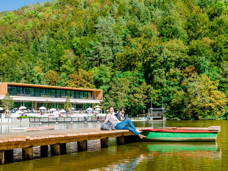 A woman sits on the dock at Thalersee with her dog. | © Graz Tourismus - Mias Photoart