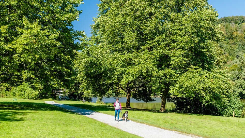 Eine Person geht mit einem Hund entlang eines Weges am Thalersee. | © Graz Tourismus - Mias Photoart