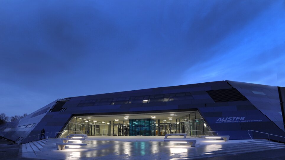 Futuristisches Schwimmbadgebäude Auster in Graz bei Dämmerung. | © Holding Graz - Helge Sommer