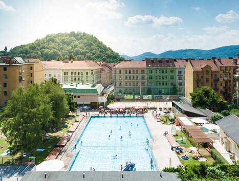 Pool with sun loungers in Graz, surrounded by buildings and trees. | © Holding Graz - Joel Kernasenko