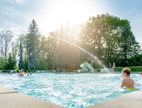View of Stukitzbad in Graz filled with swimmers and a water slide. | © Holding Graz - Joel Kernasenko