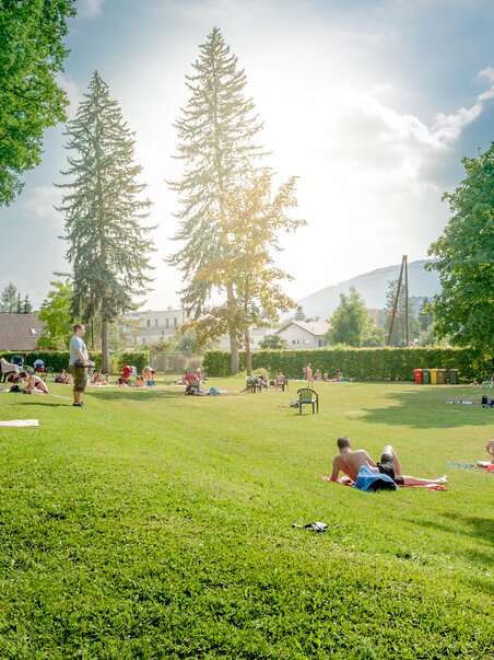 Visitors enjoy a sunny day at Stukitzbad in Graz on the lawn. | © Holding Graz - Joel Kernasenko