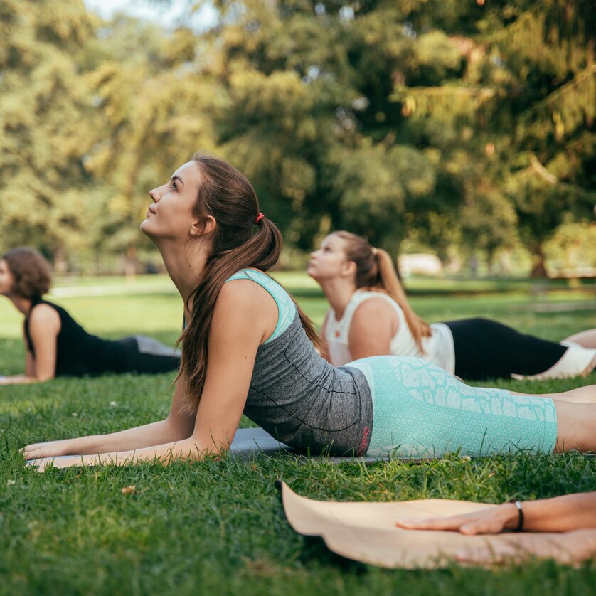 Four women practicing yoga outdoors on grass in a park. | © Graz Tourismus