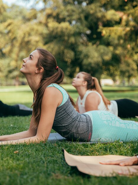 Vier Frauen praktizieren Yoga im Freien auf Rasen in einem Park. | © Graz Tourismus