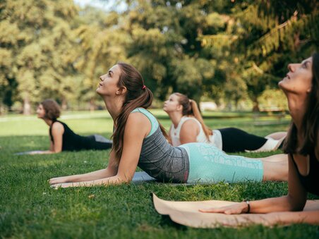 Vier Frauen praktizieren Yoga im Freien auf Rasen in einem Park. | © Graz Tourismus
