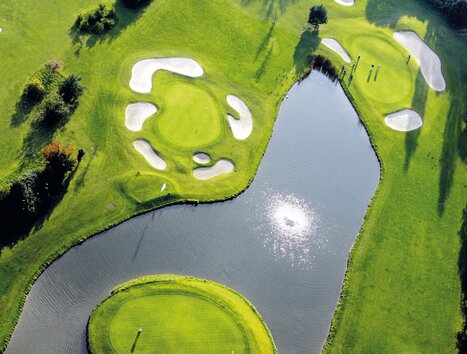 Vista aerea di un campo da golf con acqua e bunker di sabbia. | © GEPA-pictures - Murhof Gruppe