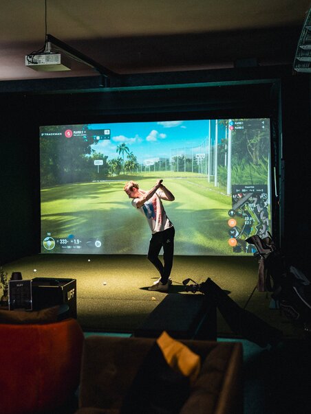 Una persona gioca a golf in un ambiente di simulazione interna. | © GEPA I RUFF Golf Graz