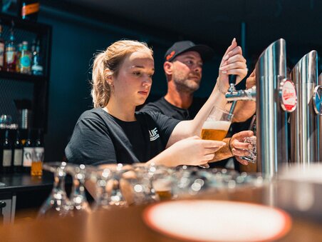 Due persone stanno spillando birra al bar, una donna e un uomo. | © GEPA I RUFF Golf Graz