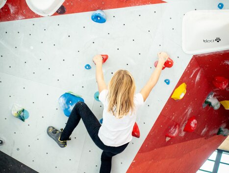 Un giovane scala su una parete di bouldering colorata. | © pixapay