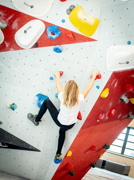 Un giovane scala su una parete di bouldering colorata. | © pixapay