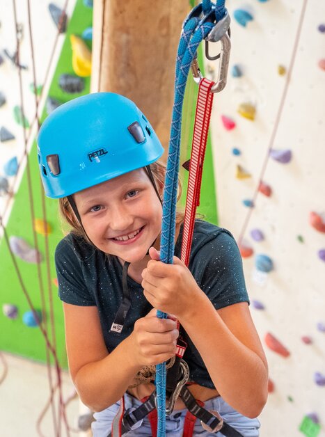 Un bambino sorridente con un casco blu mentre scala. | © C-A-C