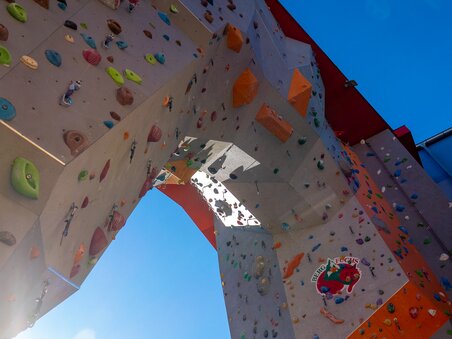 Kletterwand im City Adventure Center mit bunten Griffen und strahlend blauem Himmel. | © C-A-C
