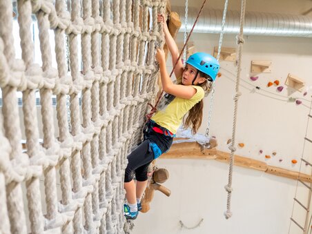 Ein Kind klettert an einem Seilnetz im Kletterzentrum. | © C-A-C
