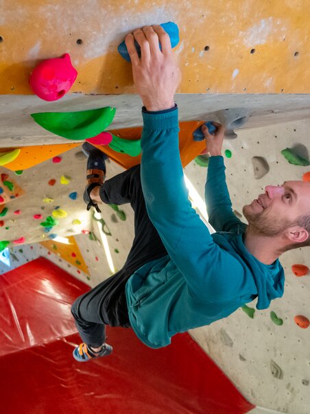 Ein Bergsteiger klettert an bunten Griffen im Kletterraum. | © C-A-C