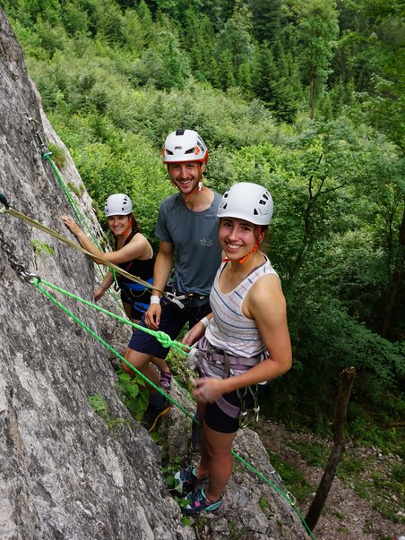 Drei Kletterer an einer Felswand im Wald, glücklich beim Klettern. | © Focus Climbing Graz